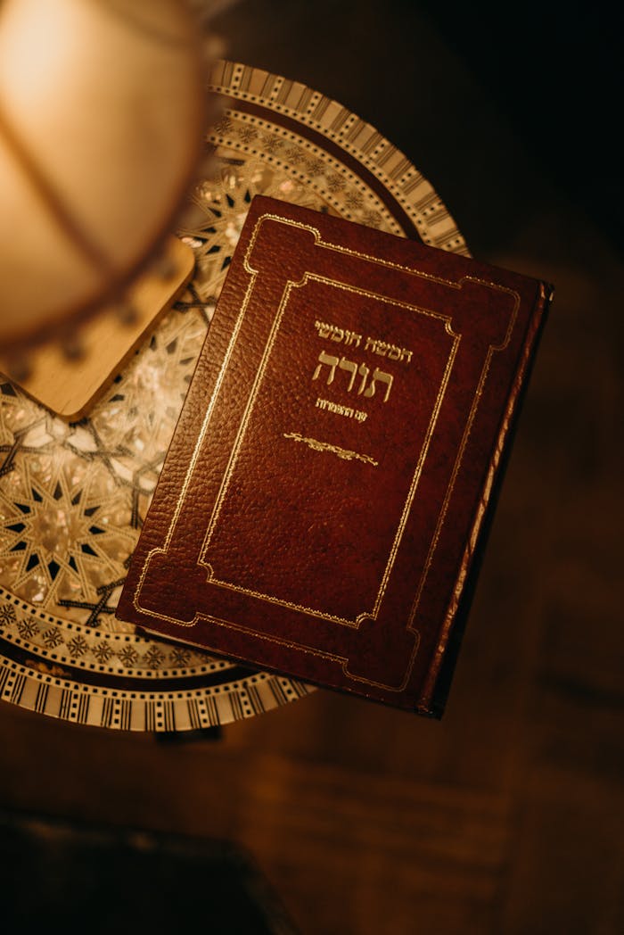A beautifully decorated Jewish book placed on an intricate table, warmly lit.