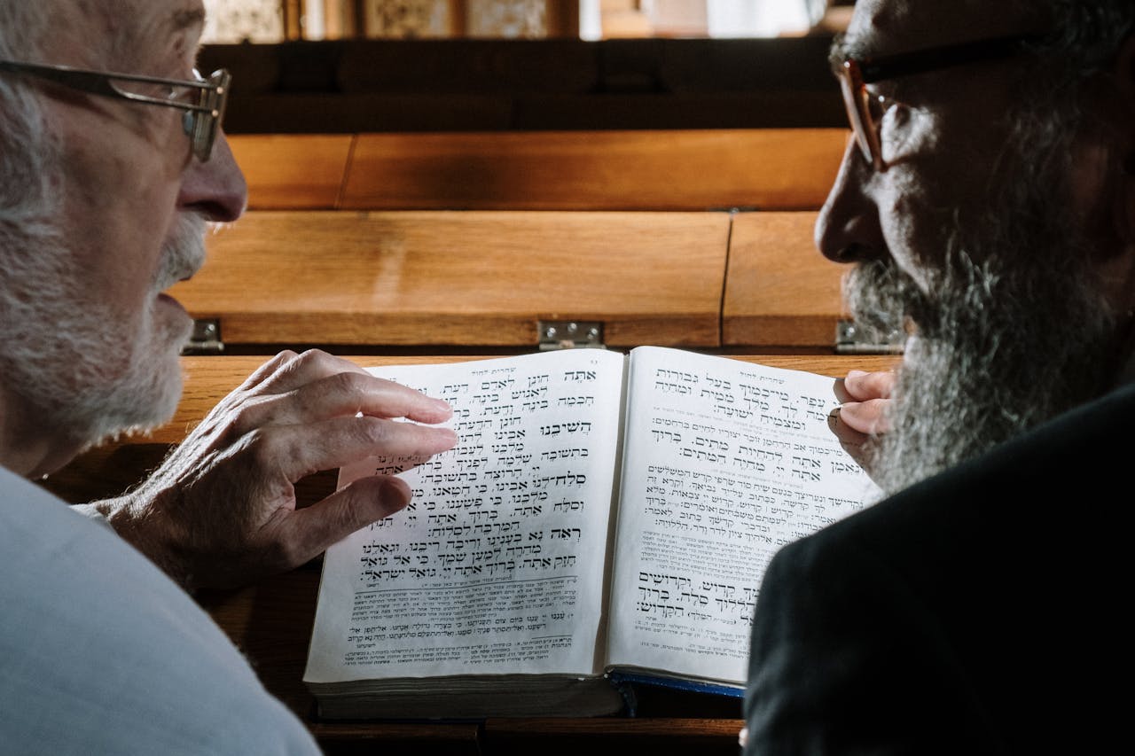 Two senior Jewish men reading a Hebrew book in a synagogue, deep in religious practice.